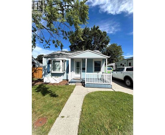 A small blue house with a white porch and a white picket fence.