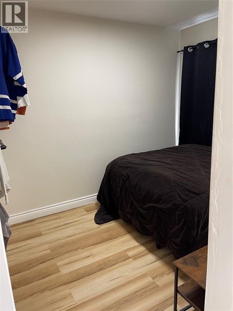 A bedroom with a bed and a wooden floor.
