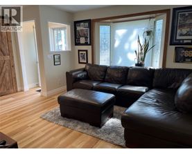 A living room with a black leather couch and ottoman.