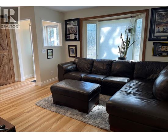 A living room with a black leather couch and ottoman.