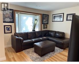 A black leather sectional sofa with ottoman in front of a window.