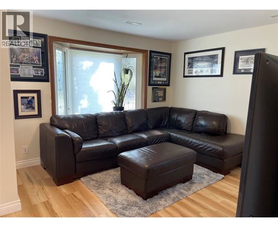 A black leather sectional sofa with ottoman in front of a window.