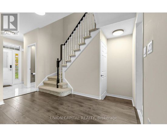 A staircase with a black railing and wooden steps leads up to a white door.