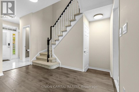 A staircase with a black railing and wooden steps leads up to a white door.