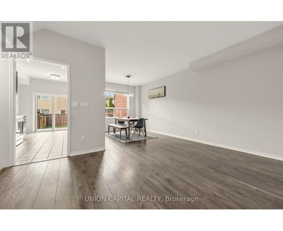 A spacious room with wooden flooring and white walls, furnished with a dining table and chairs.