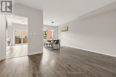 A spacious room with wooden flooring and white walls, furnished with a dining table and chairs.