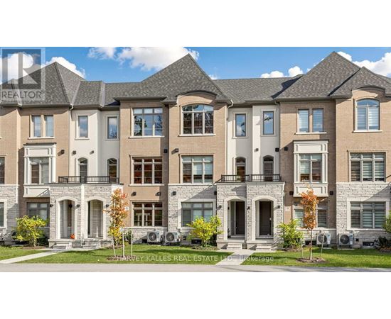 A row of townhouses with a sign that says "HARVEY KALLES REAL ESTATE".