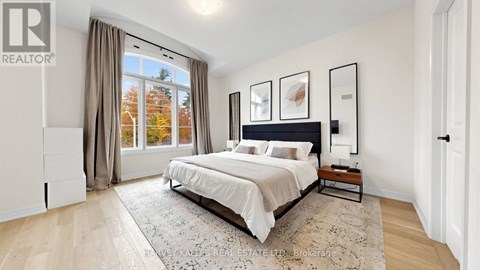 A bedroom with a large bed and a view of trees outside the window.