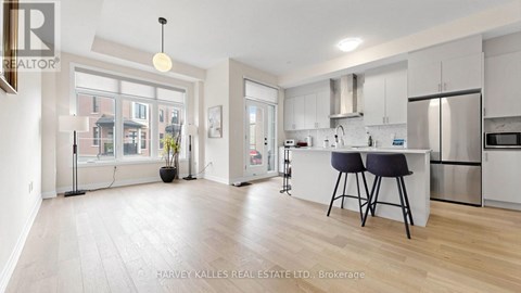 A well-lit kitchen with a dining table and bar stools.