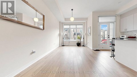 A spacious room with wooden floors and a large mirror on the wall.