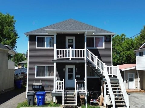 A two-story house with a grey exterior and white railings.