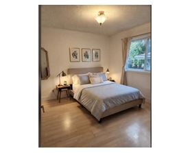 A bedroom with a bed, nightstands, and pictures on the wall.