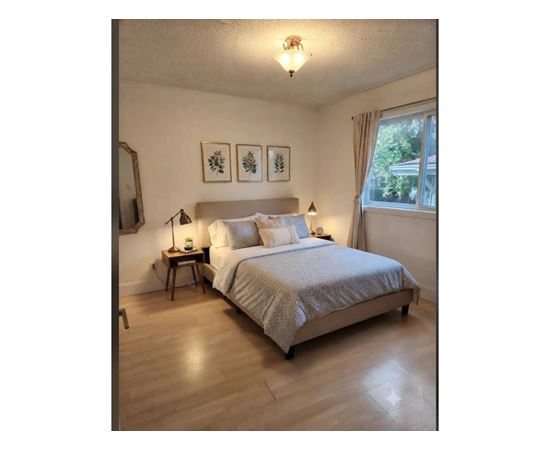 A bedroom with a bed, nightstands, and pictures on the wall.