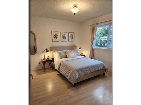 A bedroom with a bed, nightstands, and pictures on the wall.