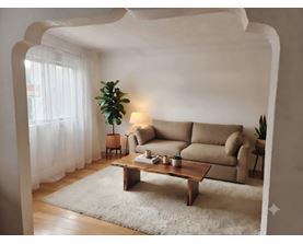 A living room with a beige sofa, a wooden coffee table, and a potted plant.