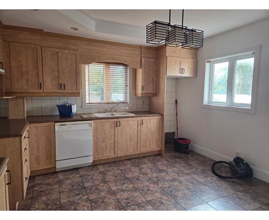 A kitchen with wooden cabinets and a tiled floor.