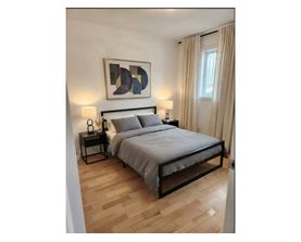 A bedroom with a bed, nightstands, and a painting on the wall.
