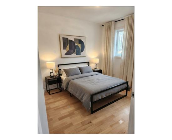 A bedroom with a bed, nightstands, and a painting on the wall.