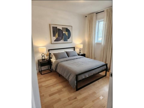 A bedroom with a bed, nightstands, and a painting on the wall.