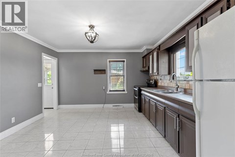 A kitchen with a white refrigerator and brown cabinets.