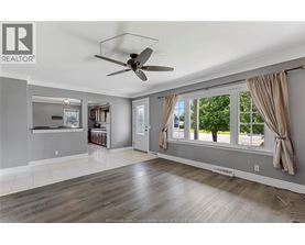 A spacious living room with a ceiling fan and large windows.