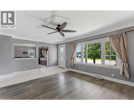 A spacious living room with a ceiling fan and large windows.