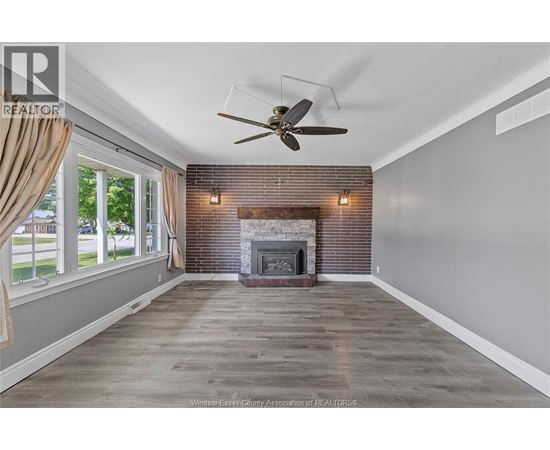 A spacious room with a fireplace and a ceiling fan.