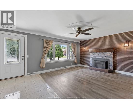A living room with a fireplace and a ceiling fan.