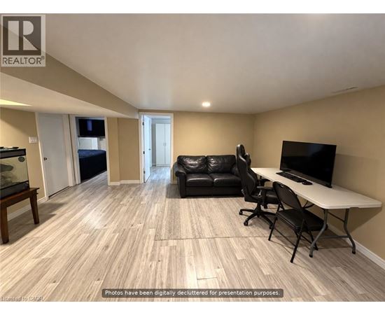 A living room with a black leather couch, a white table, and a television.