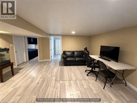 A living room with a black leather couch, a white table, and a television.