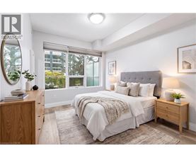 A bedroom with a large bed, a wooden nightstand, and a window with a view of the outside.