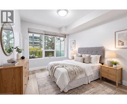 A bedroom with a large bed, a wooden nightstand, and a window with a view of the outside.