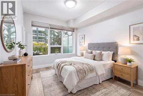 A bedroom with a large bed, a wooden nightstand, and a window with a view of the outside.