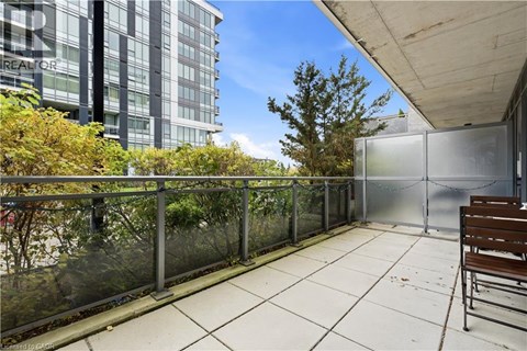 A balcony with a bench and a glass railing overlooking a tree and a building.