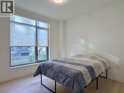 A bedroom with a bed and a window overlooking a cityscape.