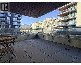A balcony with a table and chairs overlooking a cityscape.
