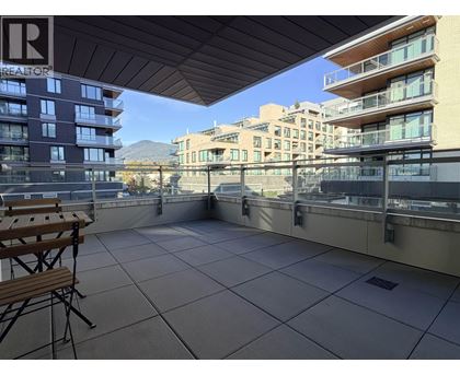 A balcony with a table and chairs overlooking a cityscape.
