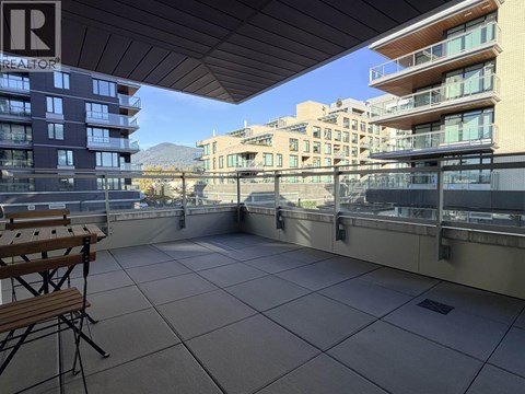 A balcony with a table and chairs overlooking a cityscape.