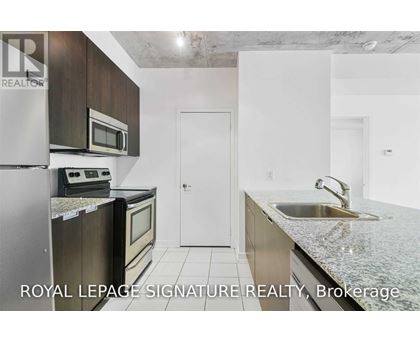A kitchen with a refrigerator, microwave, oven and sink.