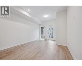 A spacious room with wooden flooring and a sliding glass door.
