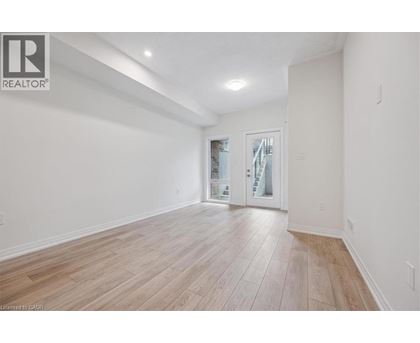 A spacious room with wooden flooring and a sliding glass door.