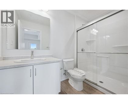 A white bathroom with a sink, toilet, and shower.