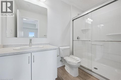 A white bathroom with a sink, toilet, and shower.
