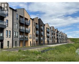 A row of modern apartment buildings with balconies and a grassy area in the foreground.