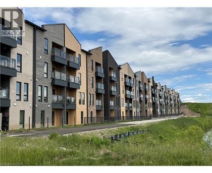 A row of modern apartment buildings with balconies and a grassy area in the foreground.