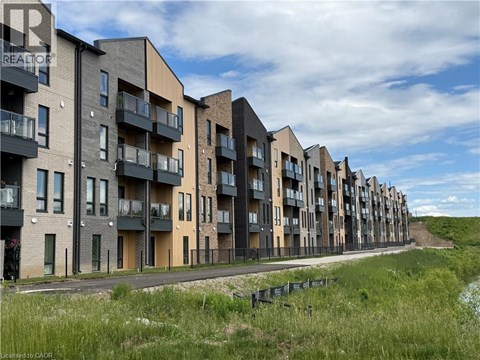A row of modern apartment buildings with balconies and a grassy area in the foreground.