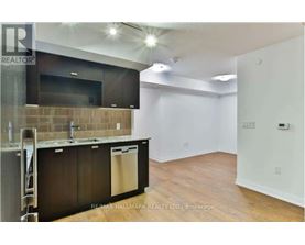 A kitchen area with a refrigerator, sink, and cabinets.