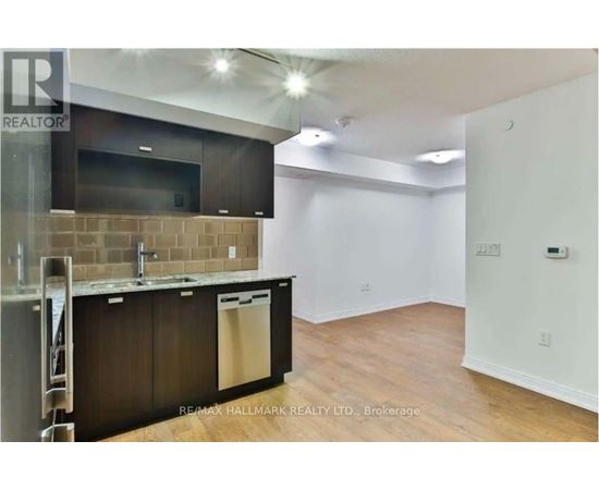 A kitchen area with a refrigerator, sink, and cabinets.