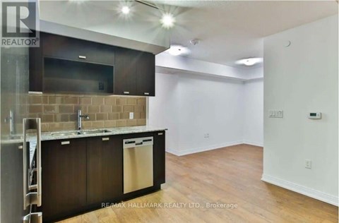 A kitchen area with a refrigerator, sink, and cabinets.