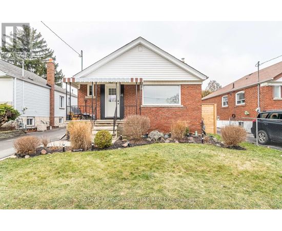 A brick house with a white door and windows is surrounded by a grassy front yard.